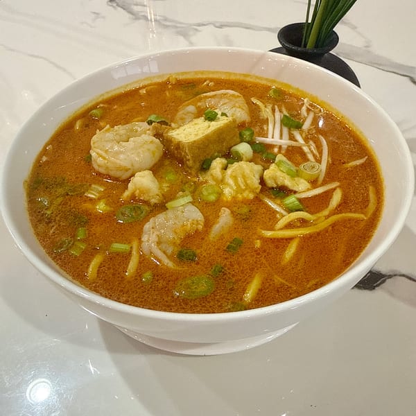 A bowl of Gourmet Asian 888's Chinese laksa with shrimp, tofu, noodles, and bean sprouts.