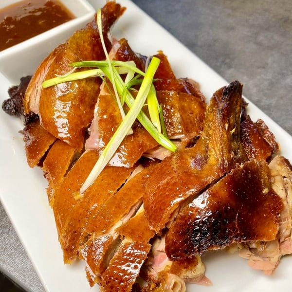 Gourmet Asian 888's sliced roasted duck with crispy skin, garnished with green onions, and a side of sauce.