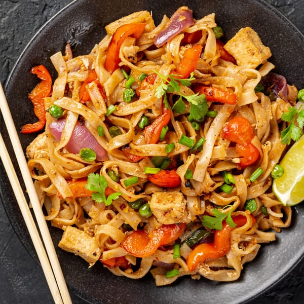 Gourmet Asian 888's Chinese noodles with tofu, red peppers, onions, and cilantro, served with chopsticks.