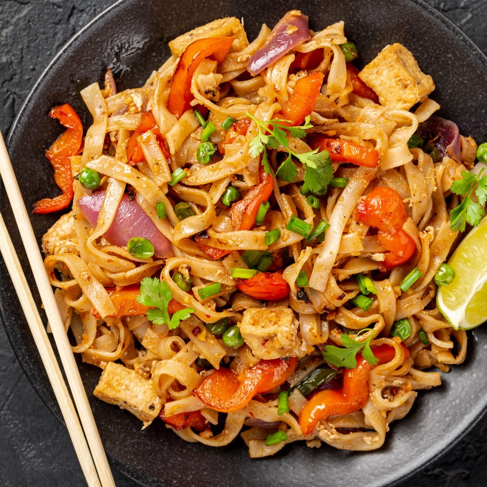 Gourmet Asian 888's Chinese noodles with tofu, red peppers, onions, and cilantro, served with chopsticks.