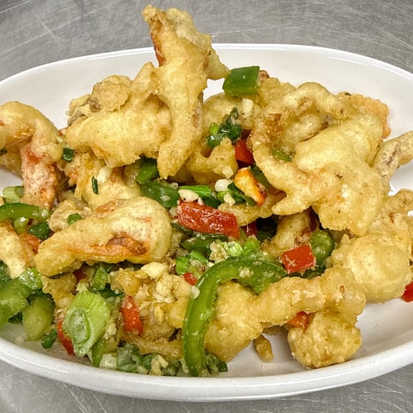 Crispy fried shrimp with red and green peppers, and scallions, served in a white bowl.