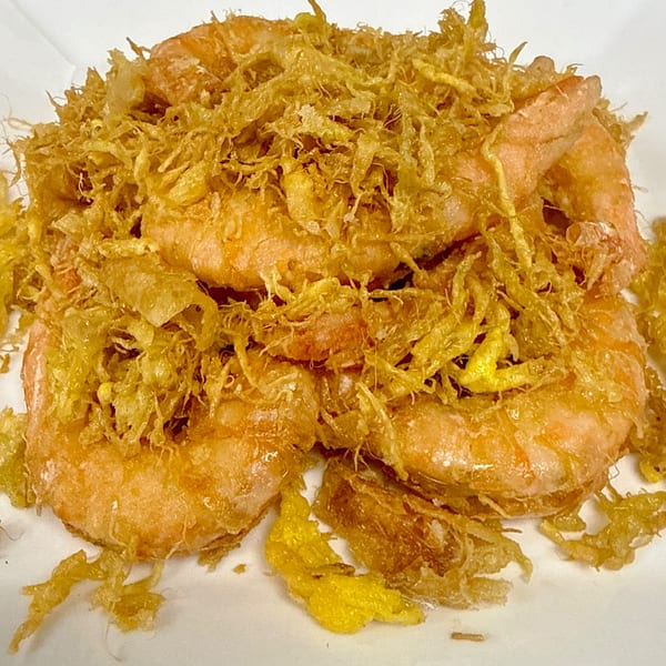 Close-up of crispy fried prawns topped with golden shredded egg floss, a Chinese delicacy.